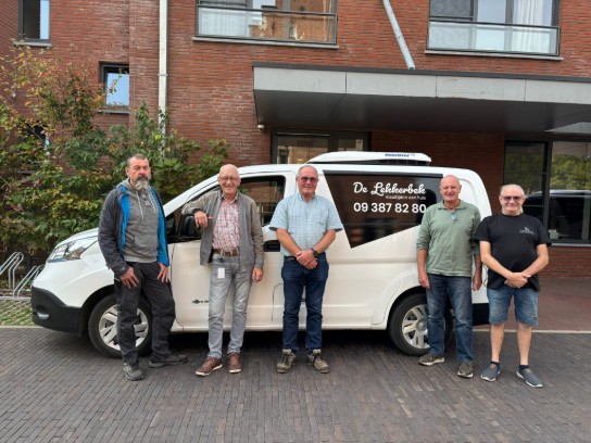Vijf mannen poseren voor een witte bestelwagen met de tekst "De Lekkerbek maaltijden aan huis" en een telefoonnummer. (vergroot foto)