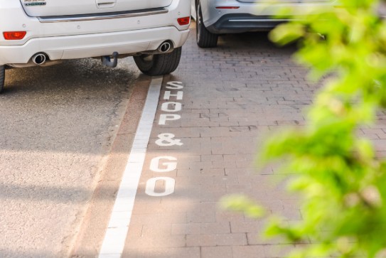 Auto geparkeerd op een plaats met de tekst "SHOP & GO" op de grond. (vergroot foto)