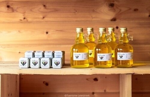 Flessen olie en blokken zeep met saffraanlabel op houten plank tegen houten achtergrond. (vergroot foto)