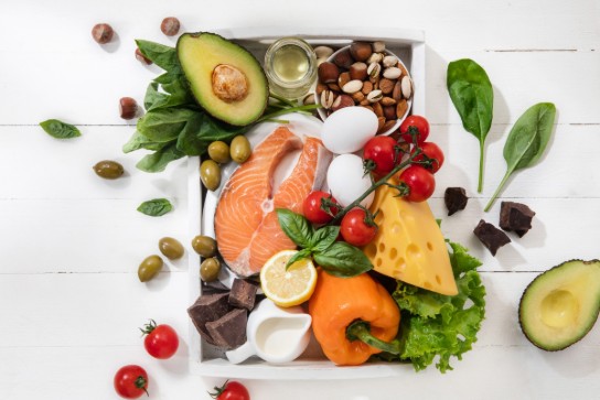 Een schaal met gezonde voedingsmiddelen zoals zalm, avocado, eieren, kaas, noten, groenten en chocolade. (vergroot foto)