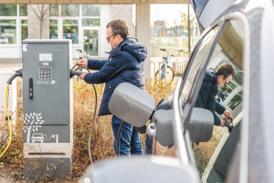 Man laadt elektrische auto op bij laadpaal buiten. (vergroot foto)