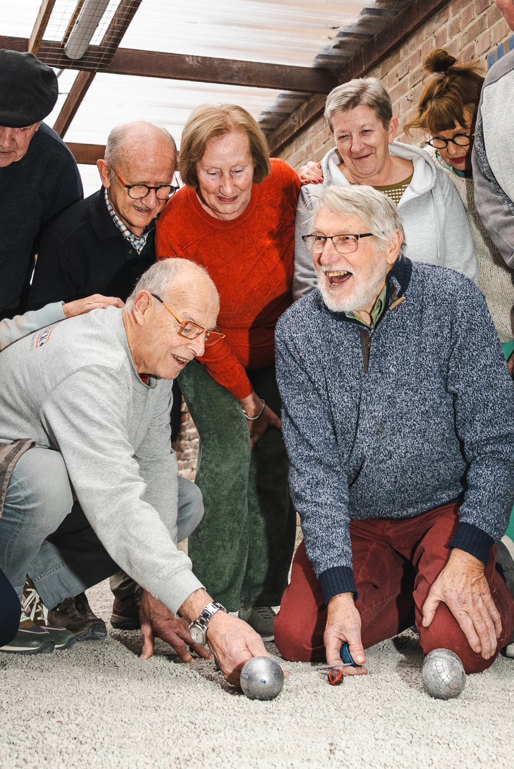 Een groep oudere mensen speelt samen jeu de boules en geniet van het spel in een overdekte ruimte.